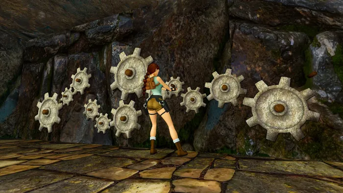 Lara Croft davanti a una parete di roccia con una serie di grandi ingranaggi di pietra