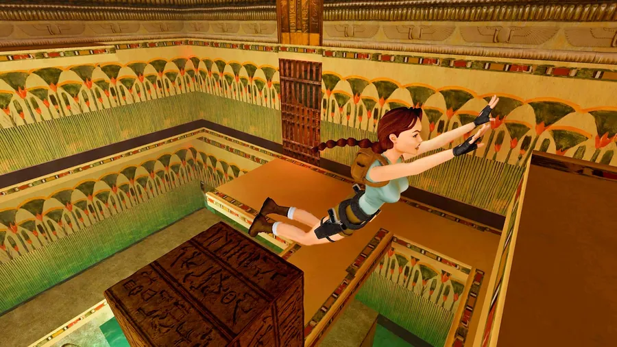 Lara Croft in salto in una sala con fregi a papiri verdi e una cassa incisa di segni